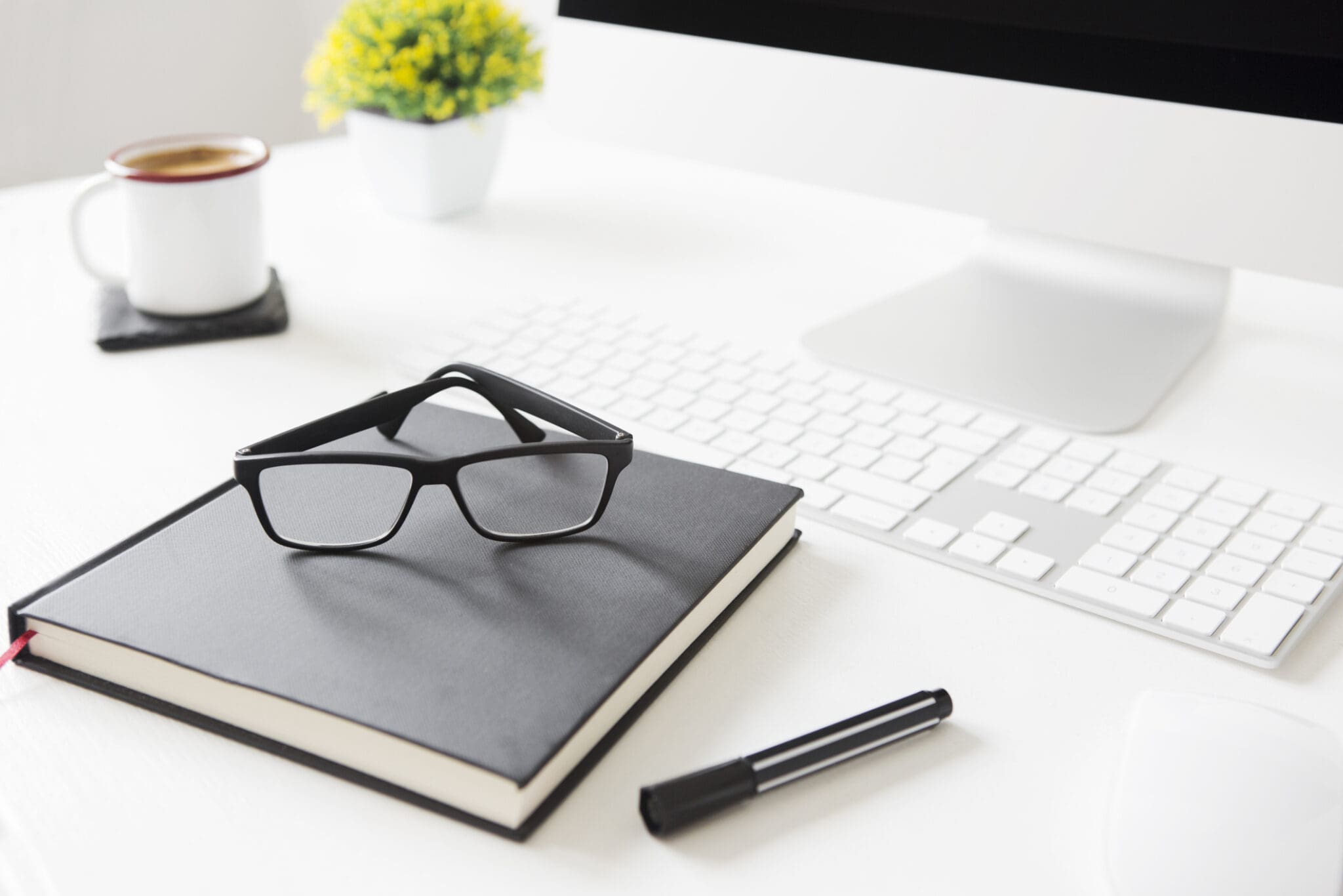 Place of work. Office desk A pair of glasses sitting on top of a book.